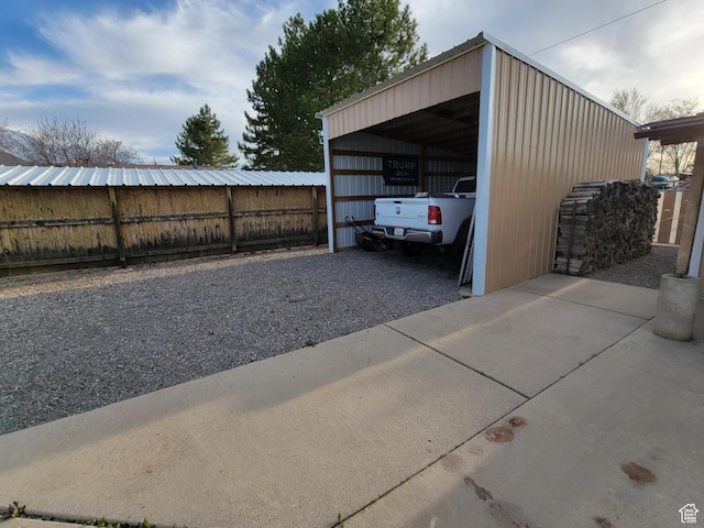 view of car parking with a detached carport, driveway, and fence