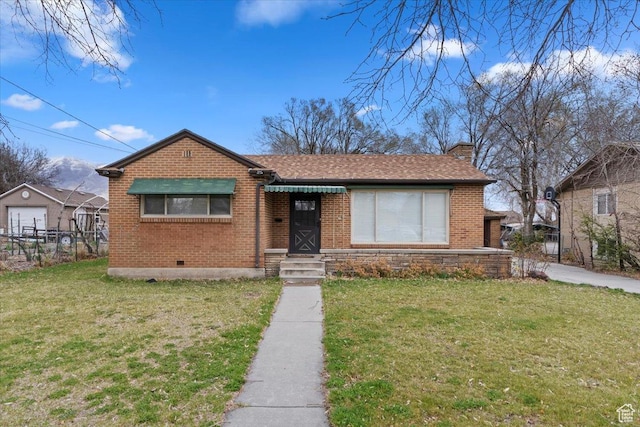 view of front facade with fence, a front yard, brick siding, and a chimney