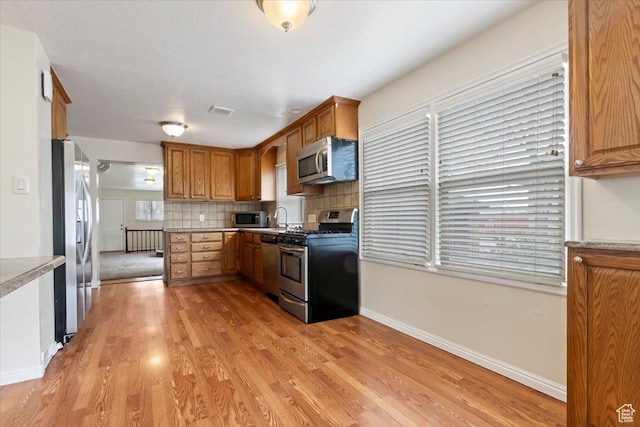 148 N 100 E, American Fork, UT 84003 - kitchen featuring visible vents, appliances with stainless steel finishes, brown cabinetry, light wood finished floors, and backsplash