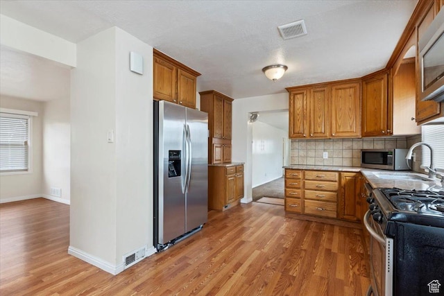 148 N 100 E, American Fork, UT 84003 - kitchen with light wood-style flooring, tasteful backsplash, brown cabinets, and stainless steel appliances