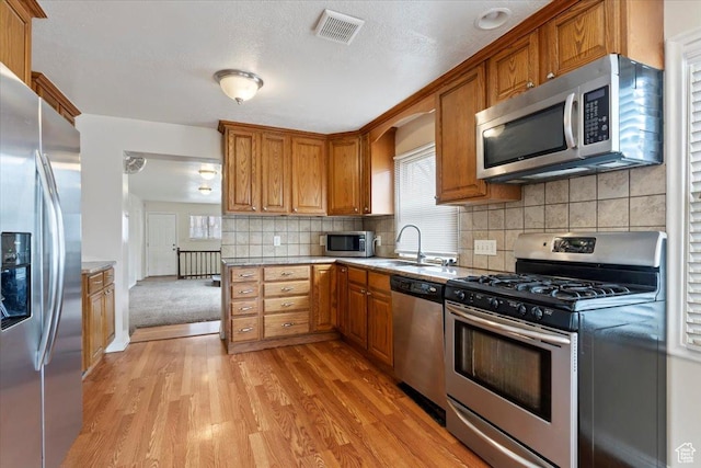 148 N 100 E, American Fork, UT 84003 - kitchen featuring brown cabinetry, appliances with stainless steel finishes, visible vents, and light wood-style flooring