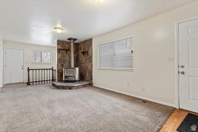 148 N 100 E, American Fork, UT 84003 - unfurnished living room featuring a wood stove, carpet flooring, a textured ceiling, and baseboards