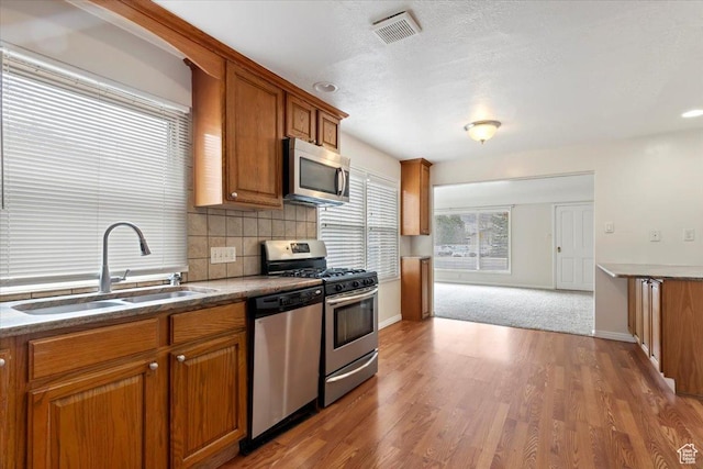 148 N 100 E, American Fork, UT 84003 - kitchen featuring visible vents, a sink, brown cabinetry, stainless steel appliances, and decorative backsplash