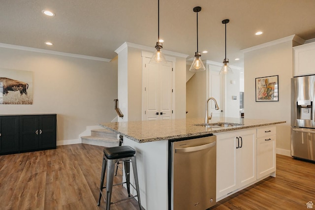 kitchen featuring a sink, ornamental molding, appliances with stainless steel finishes, and light stone countertops