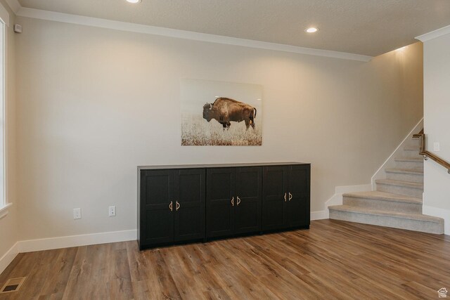 interior space featuring visible vents, baseboards, ornamental molding, light wood-style floors, and stairs