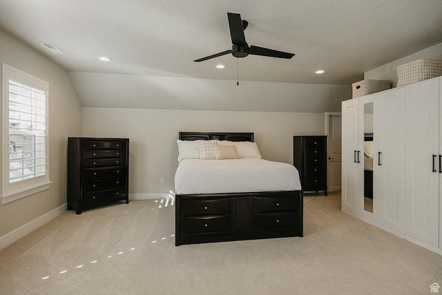 bedroom with visible vents, baseboards, a textured ceiling, light carpet, and lofted ceiling