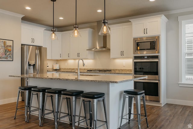 kitchen with dark wood-type flooring, wall chimney range hood, appliances with stainless steel finishes, and white cabinetry