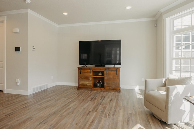 living area with visible vents, baseboards, ornamental molding, and light wood-style flooring