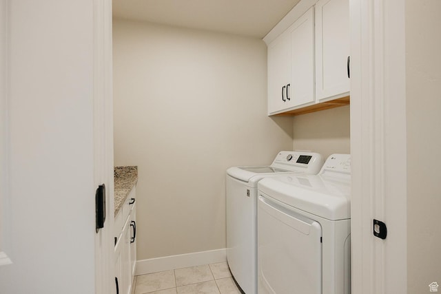 washroom featuring baseboards, washer and clothes dryer, light tile patterned flooring, and cabinet space