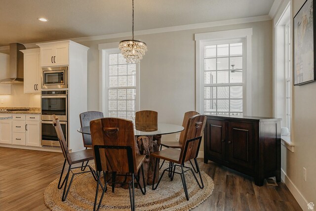 dining room with dark wood-style flooring, a notable chandelier, ornamental molding, and baseboards