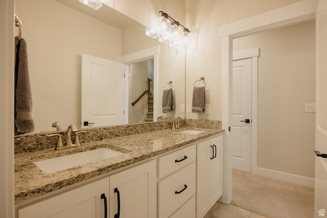 full bath with double vanity, a sink, tile patterned flooring, and baseboards