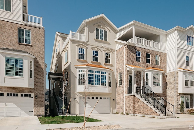 multi unit property featuring a garage, brick siding, and driveway