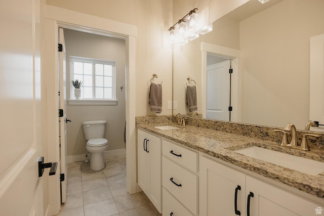 bathroom with a sink, tile patterned floors, toilet, and double vanity