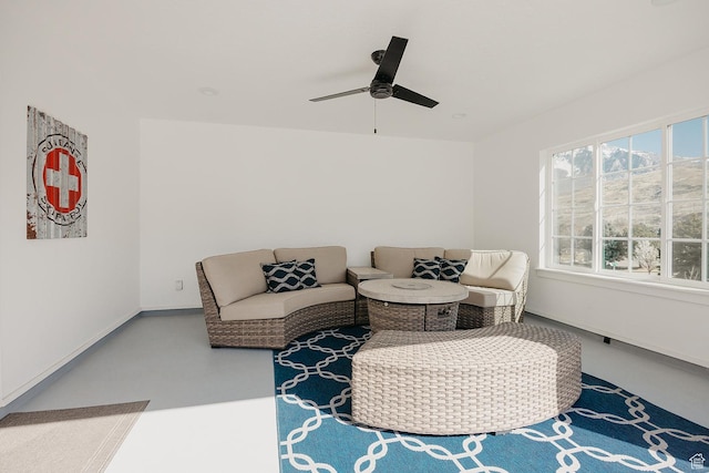 living area with finished concrete floors, baseboards, and a ceiling fan