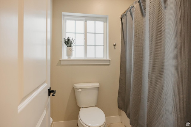 bathroom with toilet, tile patterned floors, a shower with curtain, and baseboards