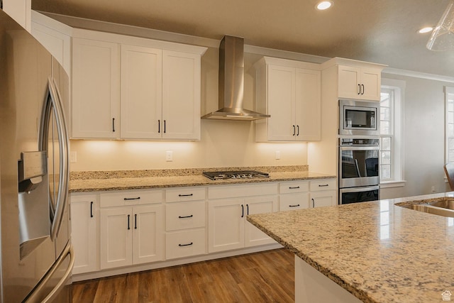 kitchen with stainless steel appliances, wall chimney exhaust hood, white cabinetry, and wood finished floors