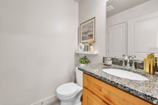 half bathroom with visible vents, toilet, vanity, and baseboards