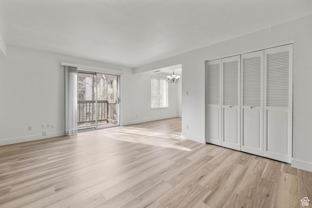 unfurnished bedroom with light wood finished floors, access to exterior, an inviting chandelier, and baseboards
