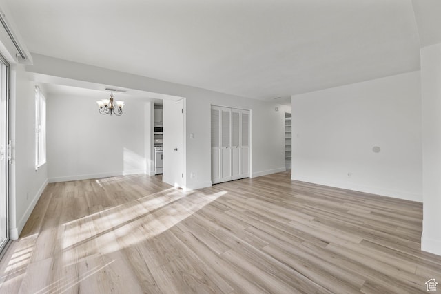 unfurnished living room with visible vents, baseboards, a chandelier, and light wood-style floors