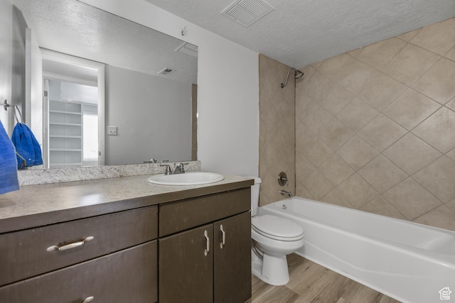 full bath with shower / washtub combination, a textured ceiling, toilet, visible vents, and wood finished floors