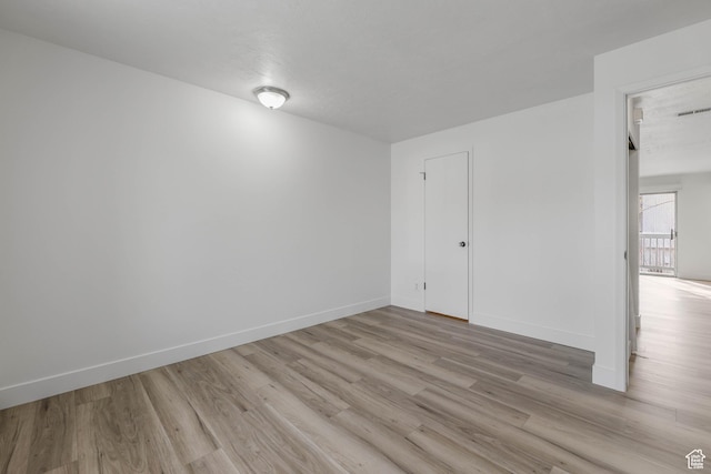 unfurnished room featuring baseboards and light wood finished floors