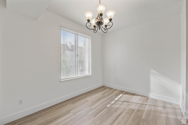 unfurnished room with light wood-style flooring, baseboards, and an inviting chandelier