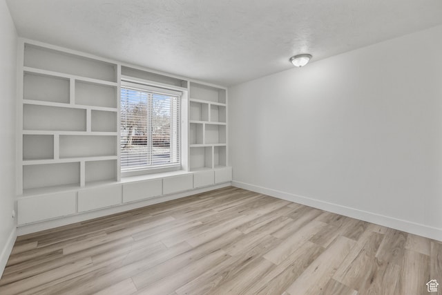 empty room featuring baseboards, wood finished floors, and a textured ceiling