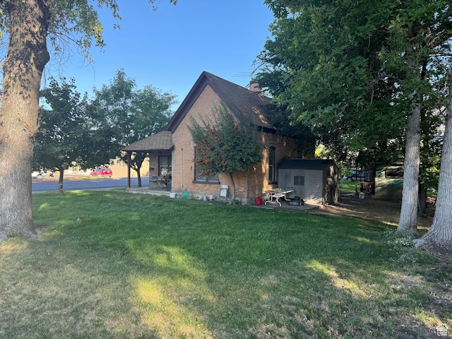 view of side of home featuring a yard, brick siding, and an outbuilding