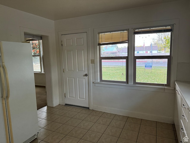 unfurnished dining area with light tile patterned floors, baseboards, and a wealth of natural light