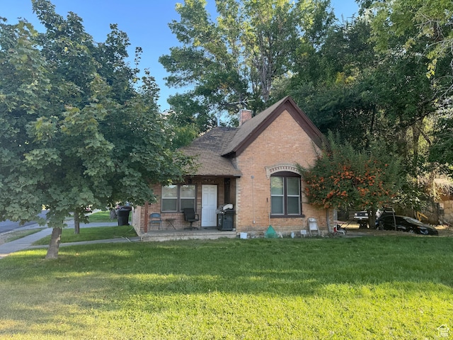 view of front of home with brick siding, a front lawn, and a chimney