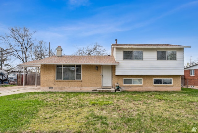 split level home featuring a chimney, a front yard, brick siding, fence, and a shingled roof