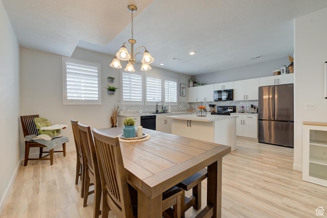 4696 W Talavera Way, Kearns, UT 84118 - dining space featuring a chandelier, light wood-style floors, baseboards, and a textured ceiling