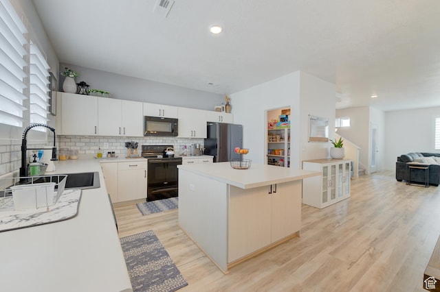 4696 W Talavera Way, Kearns, UT 84118 - kitchen with tasteful backsplash, a center island, a sink, light wood-style floors, and black appliances