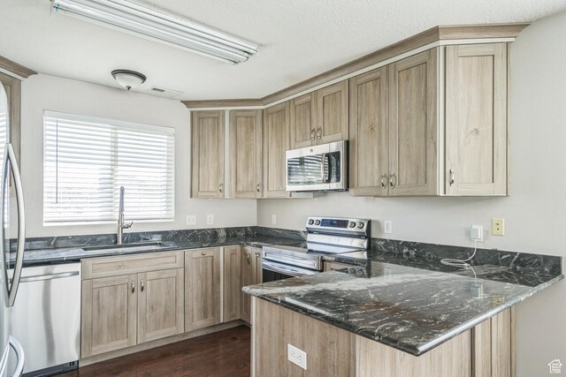 281 W Calias Ln, Stansbury Park, UT 84074 - kitchen featuring a sink, a peninsula, light brown cabinetry, dark stone counters, and stainless steel appliances