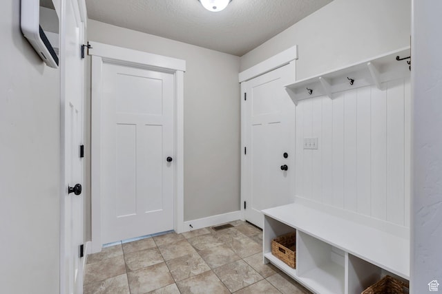2155 E Blue Sky Dr, Eagle Mountain, UT 84005 - mudroom featuring stone finish flooring, a textured ceiling, and baseboards