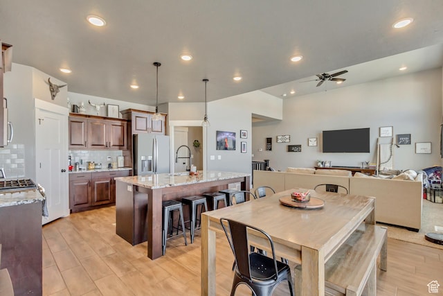 542 W Coyote Ridge Rd Unit 20, Grantsville, UT 84029 - kitchen featuring a breakfast bar, a ceiling fan, backsplash, a center island with sink, and stainless steel appliances