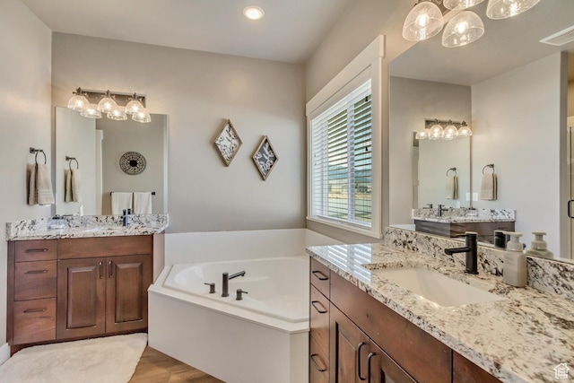 542 W Coyote Ridge Rd Unit 20, Grantsville, UT 84029 - bathroom featuring visible vents, a sink, wood finished floors, two vanities, and a garden tub
