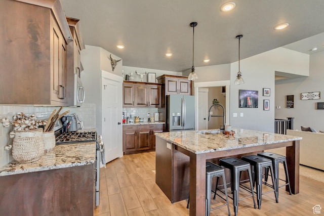 542 W Coyote Ridge Rd Unit 20, Grantsville, UT 84029 - kitchen featuring a kitchen breakfast bar, tasteful backsplash, light wood-type flooring, a sink, and stainless steel appliances