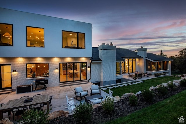 4155 S Parkview Dr, Salt Lake City, UT 84124 - back of house at dusk with brick siding, an outdoor living space with a fire pit, a patio, and a lawn