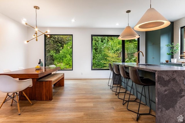 4155 S Parkview Dr, Salt Lake City, UT 84124 - kitchen featuring baseboards, an inviting chandelier, light wood-type flooring, a breakfast bar, and pendant lighting