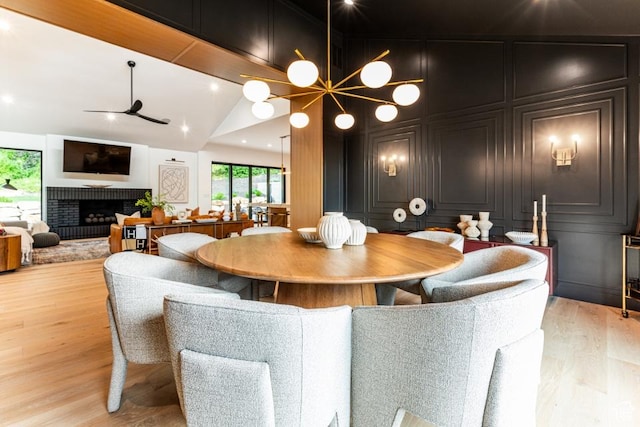4155 S Parkview Dr, Salt Lake City, UT 84124 - dining room featuring a decorative wall, light wood-type flooring, a brick fireplace, and ceiling fan with notable chandelier