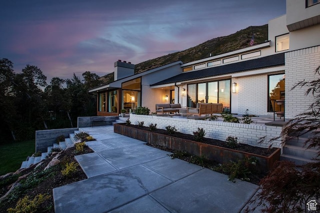 4155 S Parkview Dr, Salt Lake City, UT 84124 - back of property at dusk featuring outdoor lounge area, a patio area, a mountain view, and brick siding