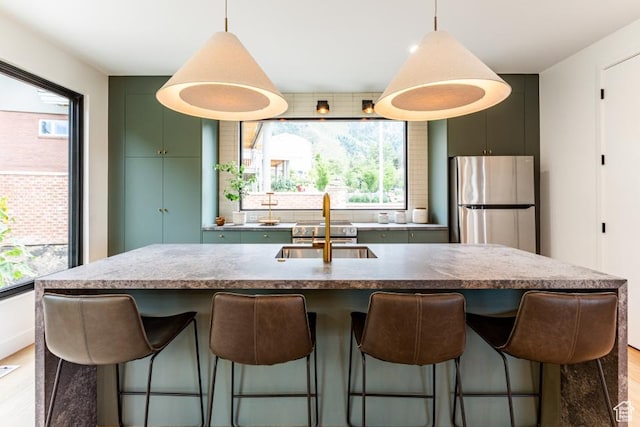 4155 S Parkview Dr, Salt Lake City, UT 84124 - kitchen with decorative light fixtures, a sink, freestanding refrigerator, a breakfast bar, and light wood-style floors