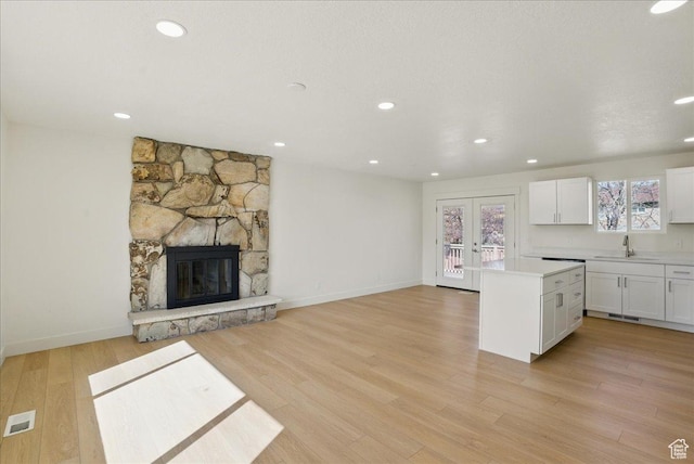 kitchen featuring white cabinetry, visible vents, a center island, light countertops, and a sink