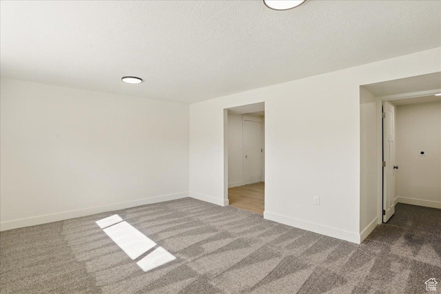 carpeted empty room featuring a textured ceiling and baseboards