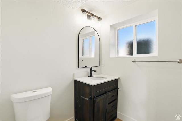 bathroom with toilet, vanity, and baseboards