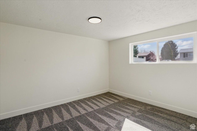 spare room with a textured ceiling, baseboards, and carpet floors