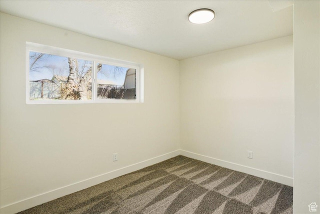 empty room featuring baseboards and dark colored carpet