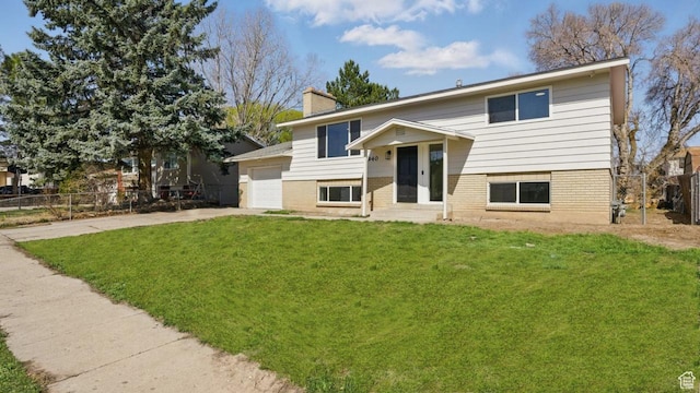 split foyer home featuring a chimney, a front lawn, fence, and concrete driveway