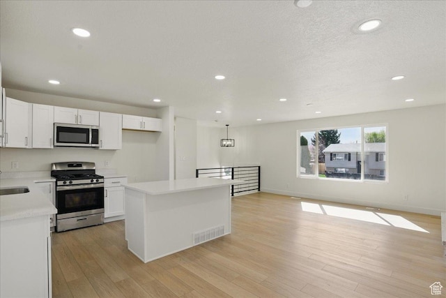 kitchen featuring white cabinets, appliances with stainless steel finishes, light countertops, and visible vents